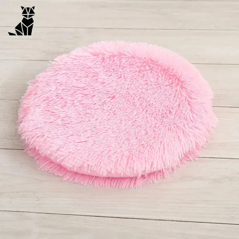 Lit rond pour petits animaux : balle rose moelleuse sur sol en bois